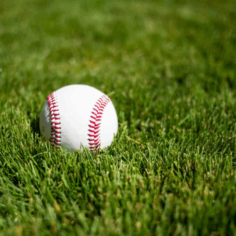 A white baseball with red stitching resting on lush green Zeon Zoysia grass