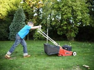 child pushing a push mower