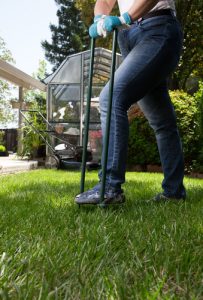 worker aerating a lawn